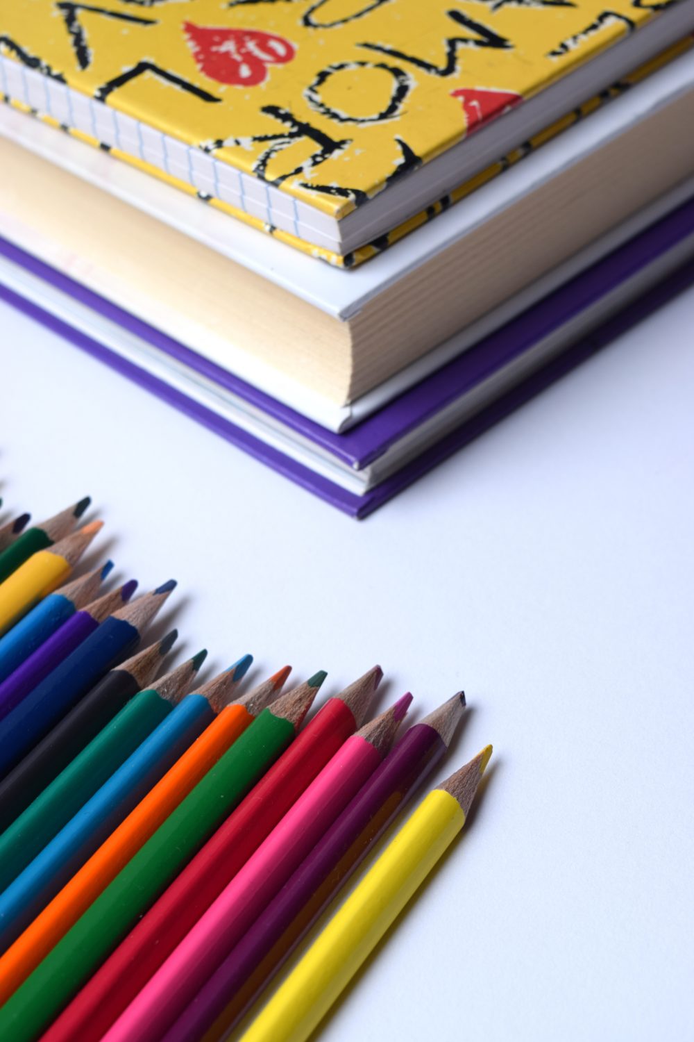 livros empilhados e lápis de cor enfileirados