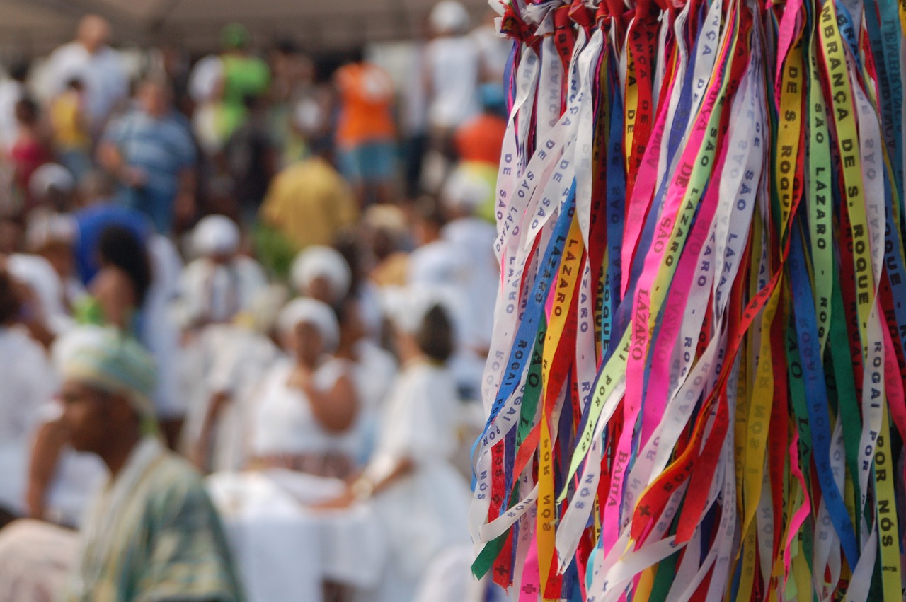 Fitas coloridas de santos em primeiro plano e ao fundo várias baianas vestidas de branco