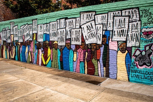 Mural pintado com várias pessoas segurando cartazes