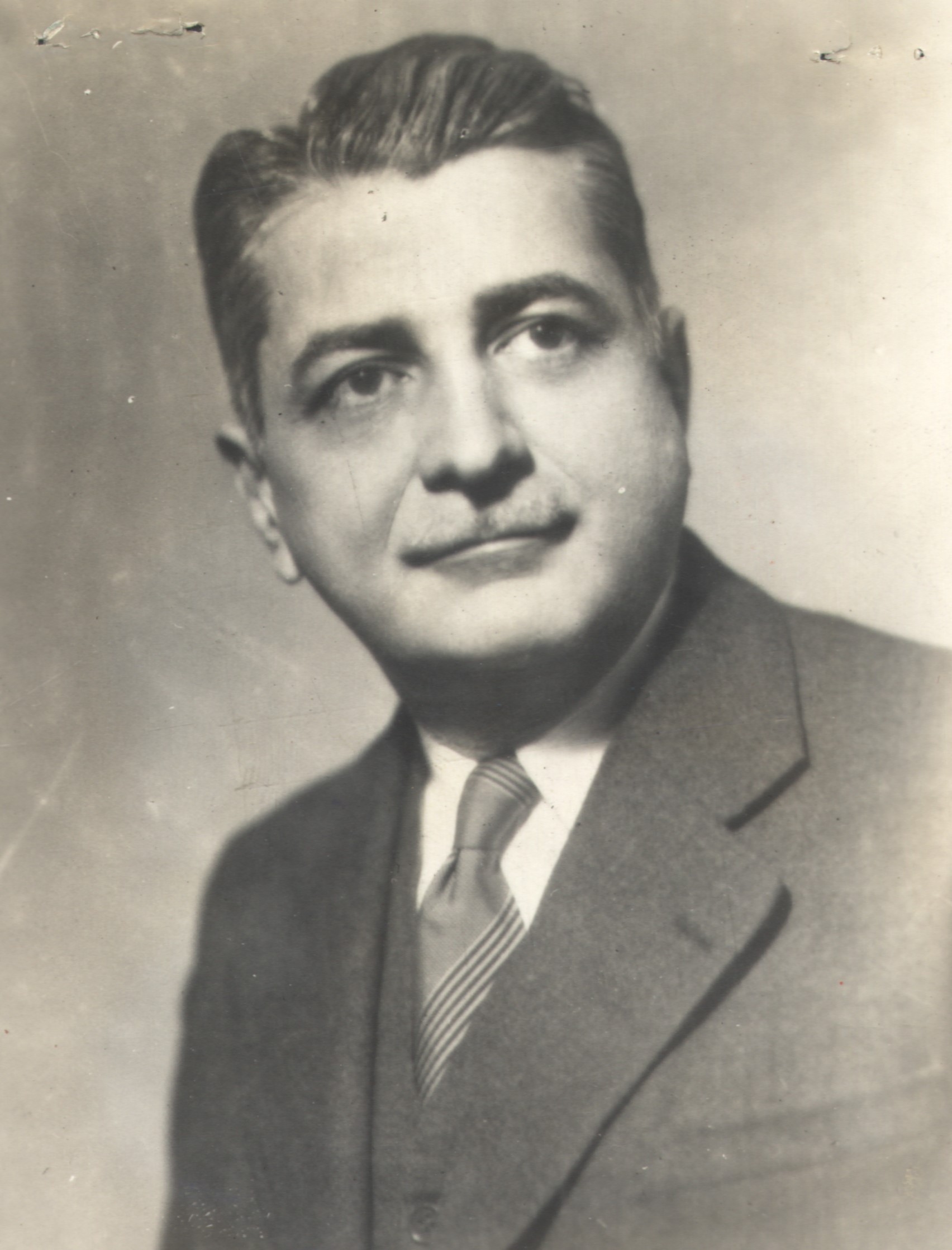 Retrato de Gilberto Freyre em preto e branco. O sociólogo está de terno e gravata, com o cabelo penteado para trás e com bigodes.